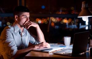 A man on his computer at night after working mandatory overtime in California