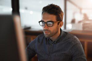 An employee continues working at a computer while wondering how many hours straight you can legally work in a day.