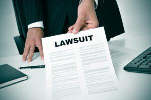 A piece of paper with “Lawsuit” written on it, with someone nearby wondering how much you can sue an employer for misclassification