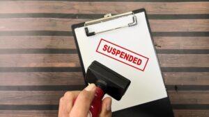 A piece of paper with “Suspended” written on it, with someone nearby who was suspended from work pending an investigation and is unsure about what their rights are in California.